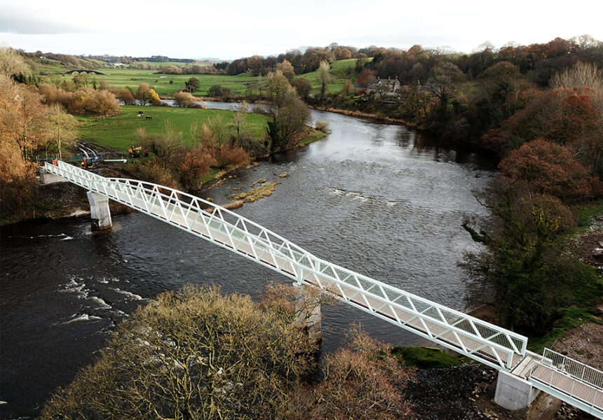 Aerial view of a bridge spanning a river, showcasing the water and surrounding landscape from above.